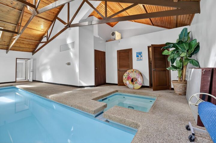 Indoor pool and hot tub with walls of windows to the woods