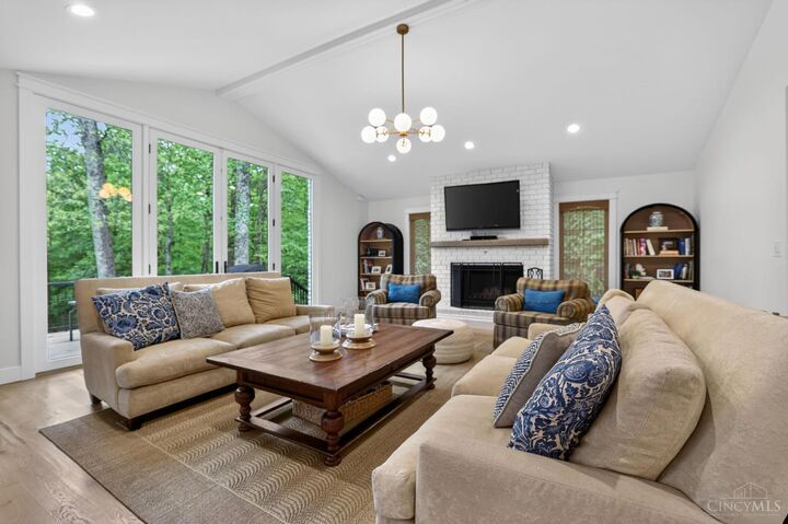 Living room with vaulted ceiling and a wall of windows overlooking the woods